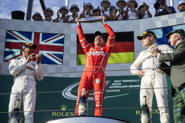 Lewis Hamilton (GBR) Mercedes AMG F1, race winner Sebastian Vettel (GER) Ferrari and Valtteri Bottas (FIN) Mercedes AMG F1 celebrate on the podium with the trophy at Formula One World Championship, Rd1, Australian Grand Prix, Race, Albert Park, Melbourne, Australia, Sunday 26 March 2017. Lewis Hamilton (GBR) Mercedes AMG F1, race winner Sebastian Vettel (GER) Ferrari and Valtteri Bottas (FIN) Mercedes AMG F1 celebrate on the podium with the trophy at Formula One World Championship, Rd1, Australian Grand Prix, Race, Albert Park, Melbourne, Australia, Sunday 26 March 2017.